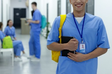 Photo of Medical student in uniform with backpack and notebook at university, selective focus