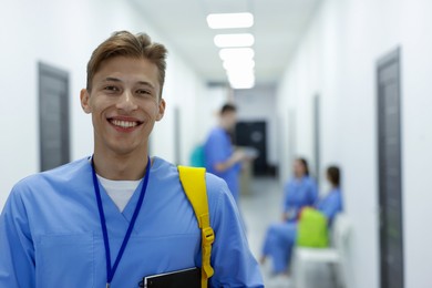 Photo of Medical student in uniform with backpack at university, selective focus