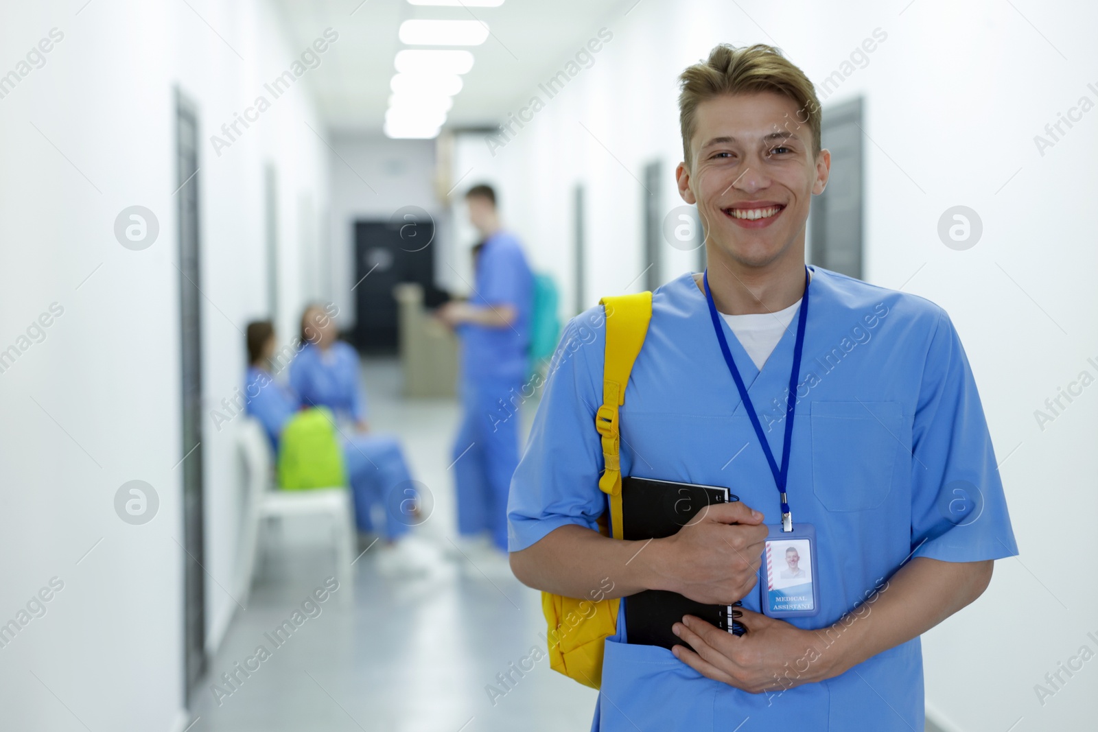 Photo of Medical student in uniform with backpack and notebook at university, selective focus
