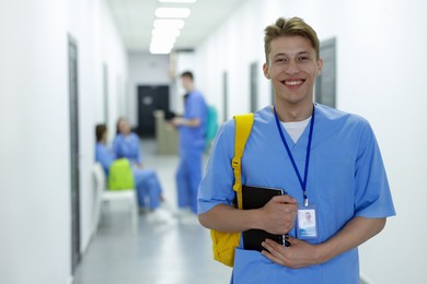 Photo of Medical student in uniform with backpack and notebook at university, selective focus