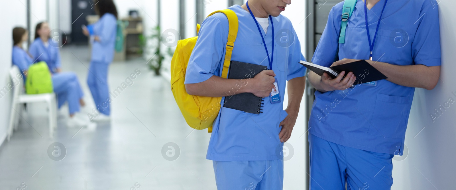 Photo of Medical student in uniforms with backpacks and notebooks at university, selective focus