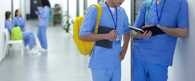 Photo of Medical student in uniforms with backpacks and notebooks at university, selective focus