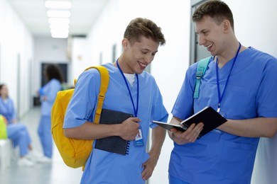 Photo of Medical student in uniforms with backpacks and notebooks at university, selective focus