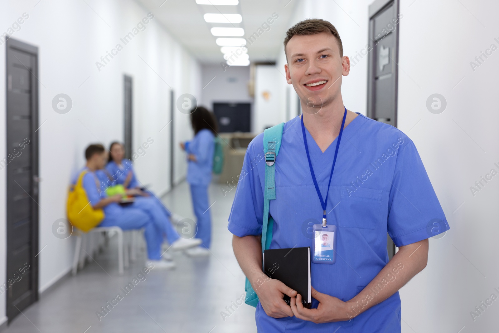 Photo of Medical student in uniform with backpack and notebook at university, selective focus