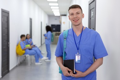 Photo of Medical student in uniform with backpack and notebook at university, selective focus