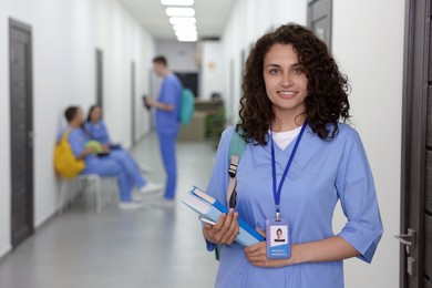 Photo of Medical student in uniform with books indoors, selective focus