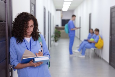 Photo of Medical student in uniform with books indoors, selective focus