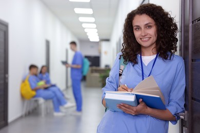 Photo of Medical student in uniform with books indoors, selective focus