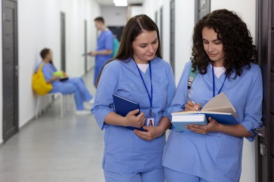Photo of Medical students in uniforms studying together indoors, selective focus