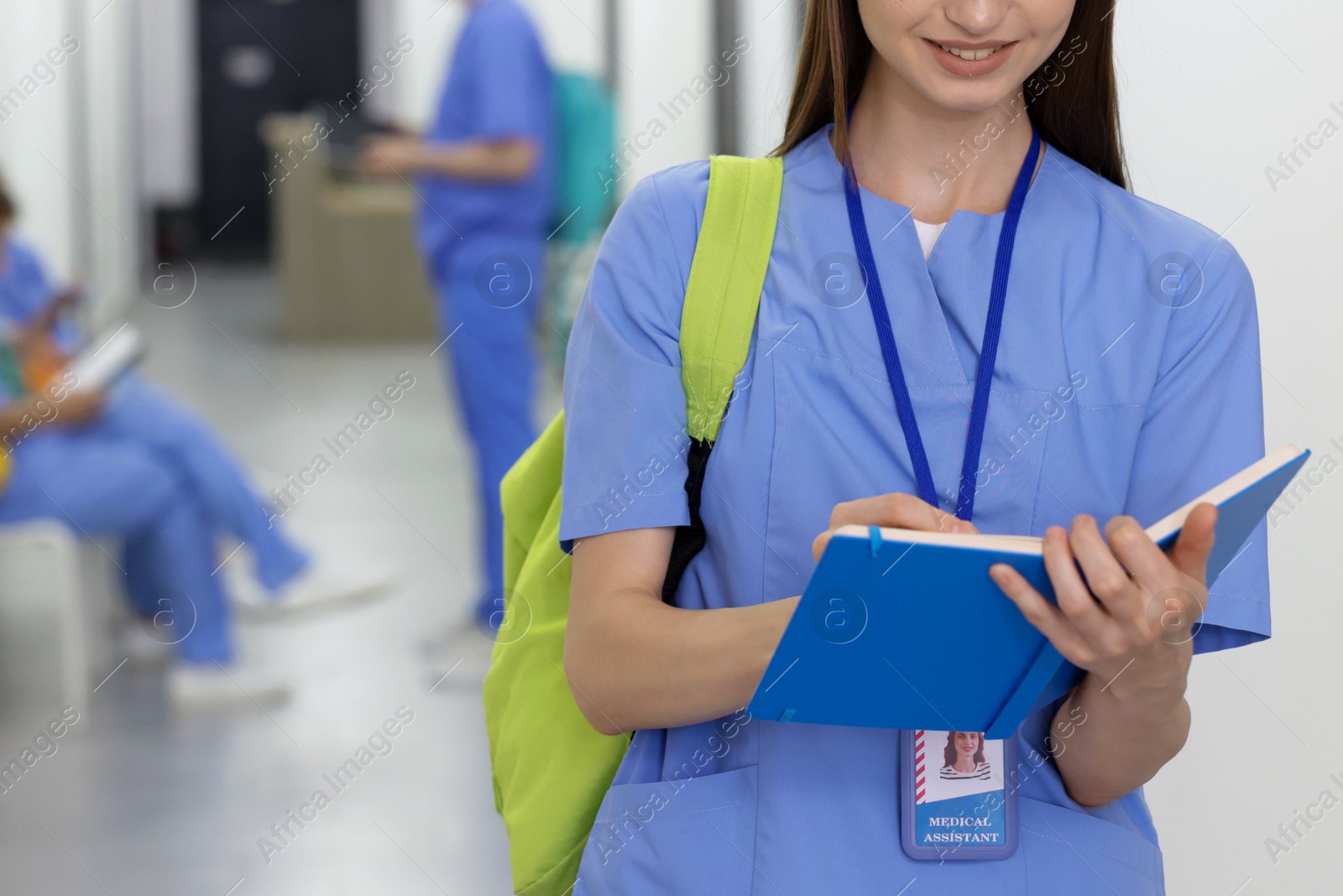 Medical student in uniform with backpack and notebook indoors, selective focus Photo of Medical student in uniform with backpack and notebook indoors, selective focus
