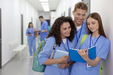 Photo of Medical students in uniforms studying together indoors, selective focus