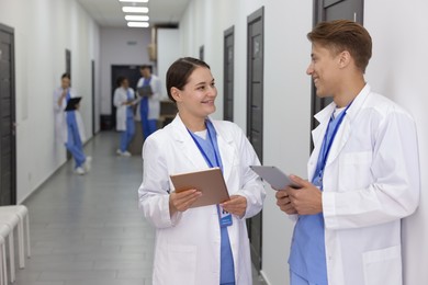 Photo of Medical students in uniforms with tablets indoors, selective focus