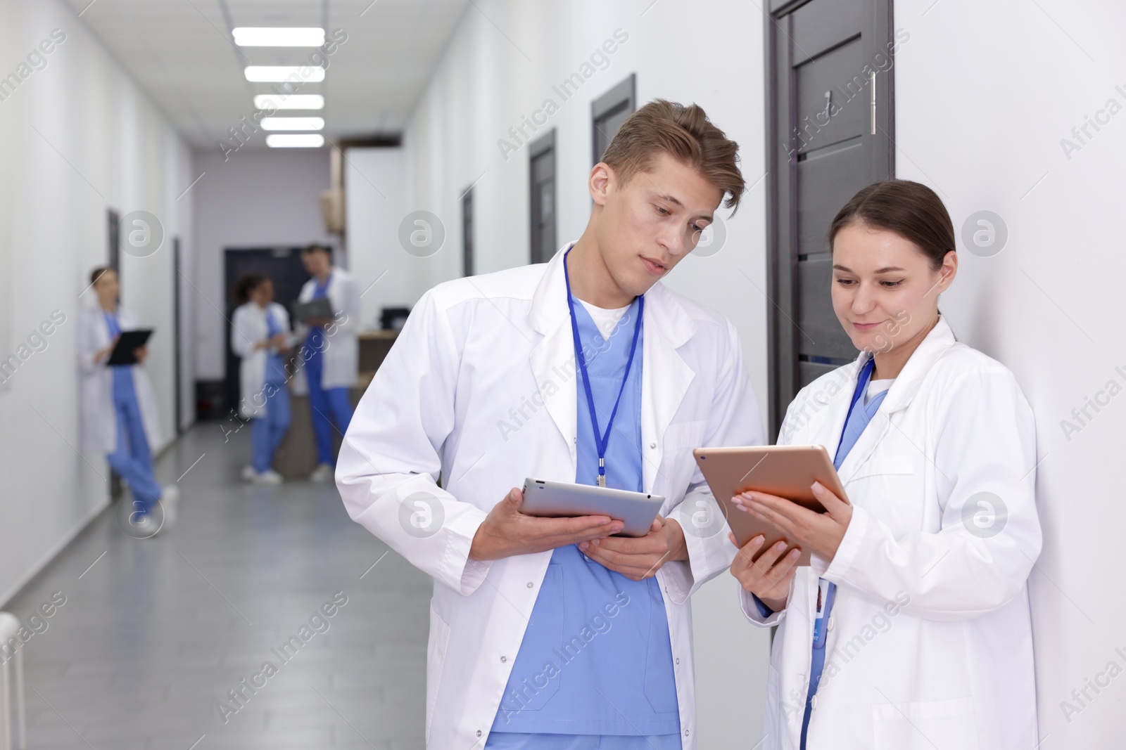 Medical students in uniforms with tablets indoors, selective focus Photo of Medical students in uniforms with tablets indoors, selective focus