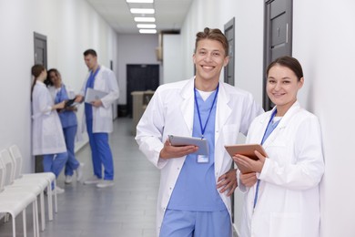 Photo of Medical students in uniforms with tablets indoors, selective focus