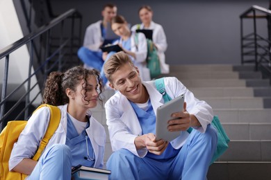 Photo of Group of medical students in uniforms on stairs indoors, low angle view