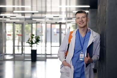 Photo of Medical student in uniform with backpack and laptop indoors, space for text