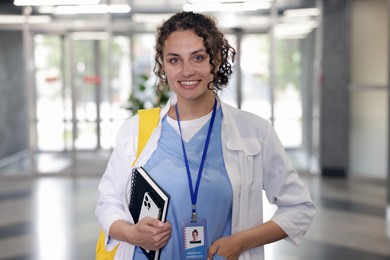 Photo of Medical student in uniform with notebook and smartphone indoors