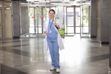 Photo of Medical student in uniform with backpack indoors