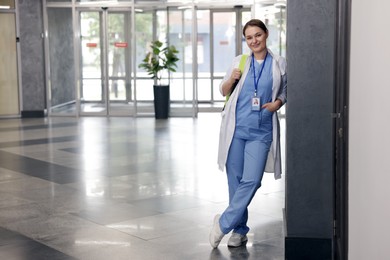 Photo of Medical student in uniform with backpack indoors, space for text