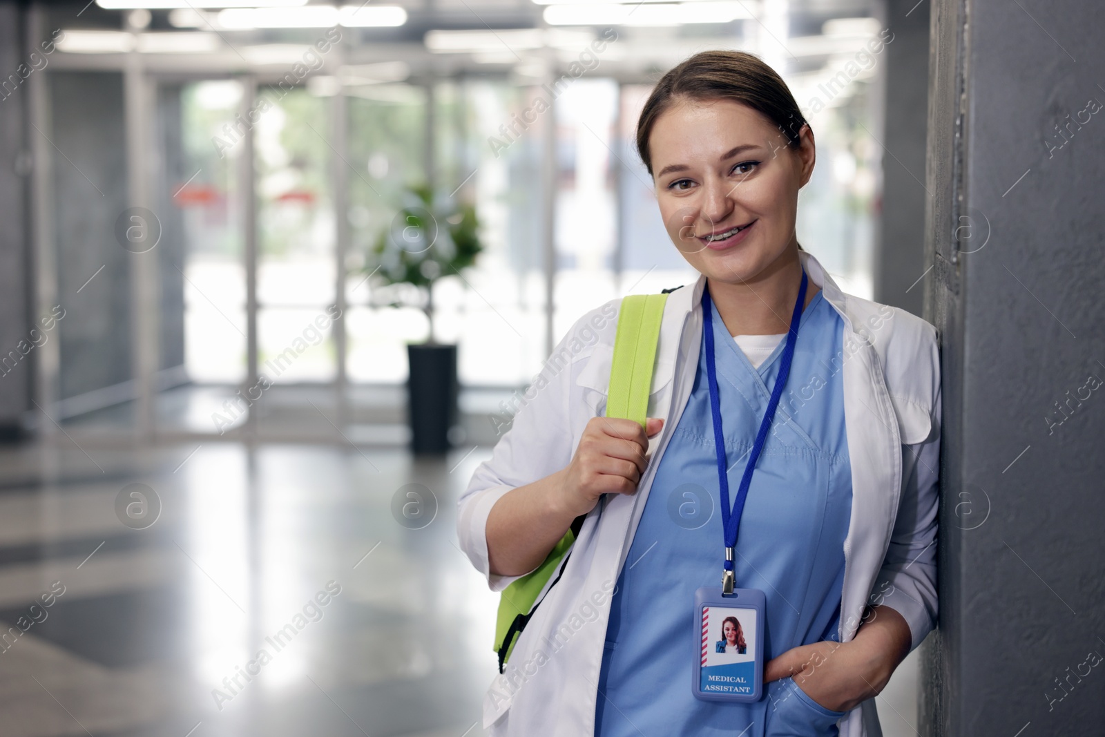 Photo of Medical student in uniform with backpack indoors, space for text
