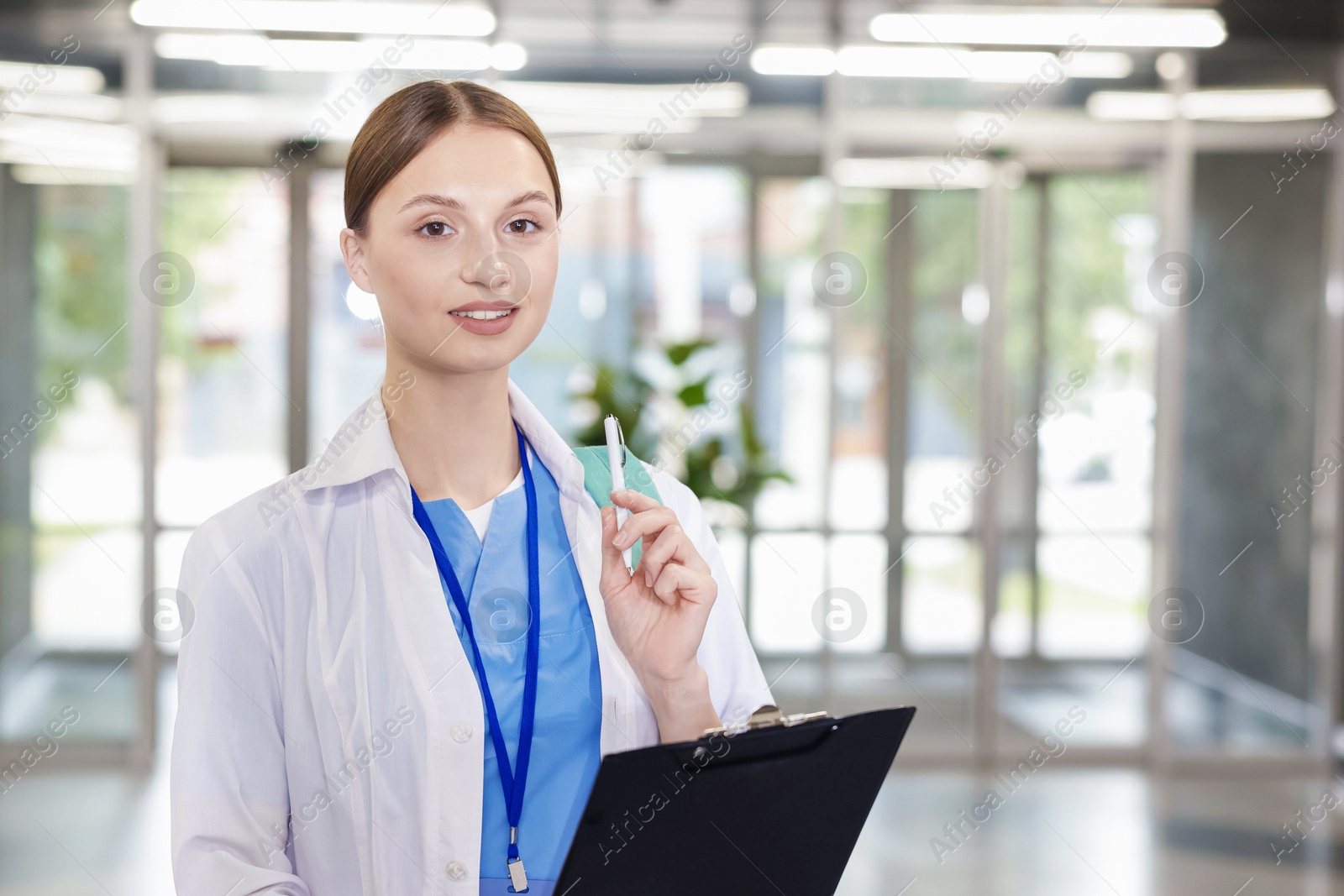 Medical student in uniform with backpack and clipboard indoors Photo of Medical student in uniform with backpack and clipboard indoors