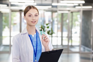 Photo of Medical student in uniform with backpack and clipboard indoors