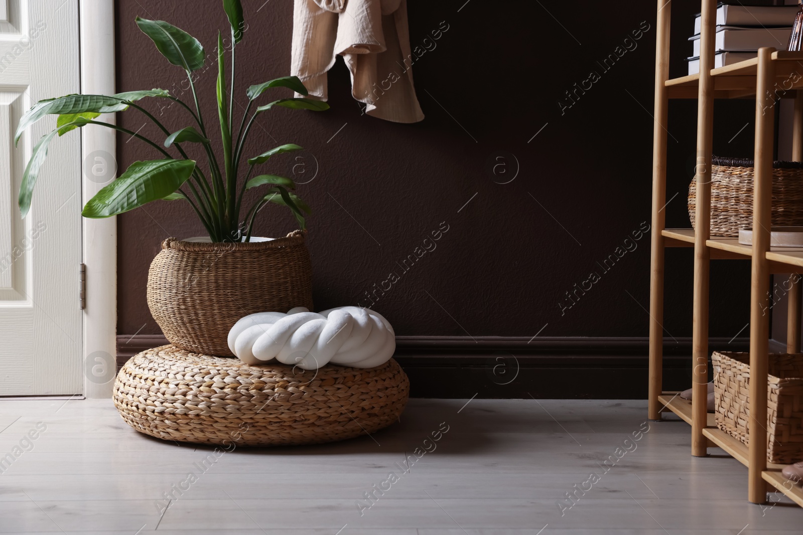 Stylish wicker pouf with houseplant and cushion at home Photo of Stylish wicker pouf with houseplant and cushion at home
