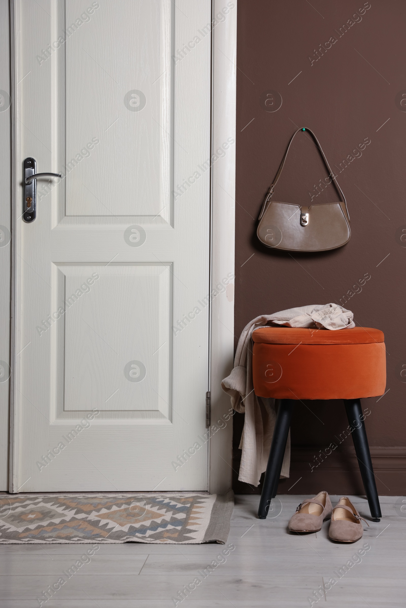 Stylish pouf with shirt and shoes near door at home Photo of Stylish pouf with shirt and shoes near door at home
