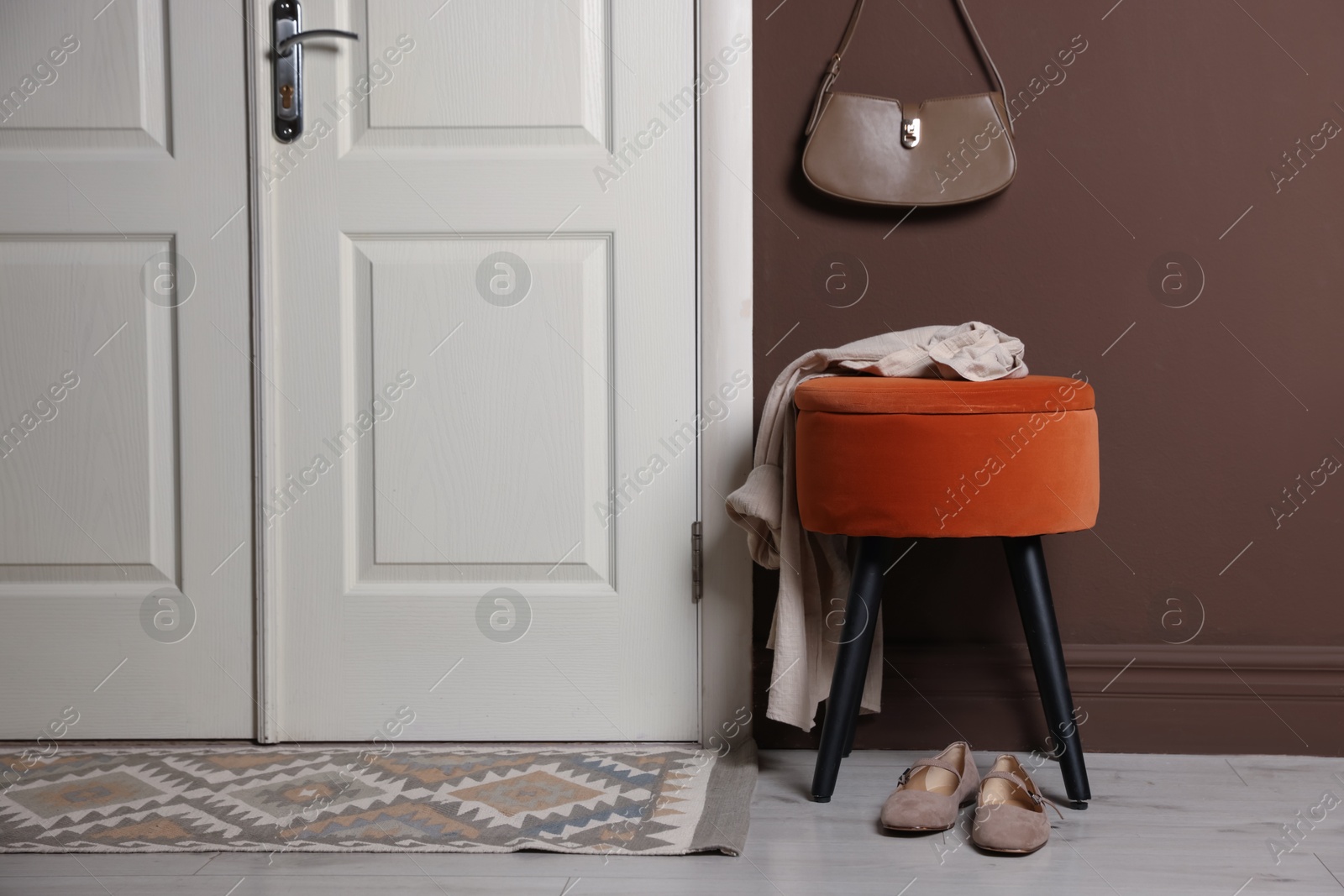 Stylish pouf with shirt and shoes near door at home Photo of Stylish pouf with shirt and shoes near door at home