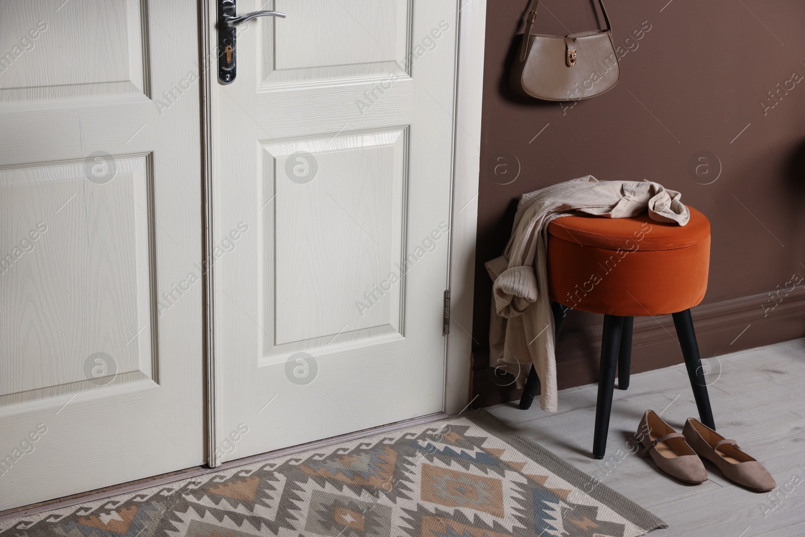Stylish pouf with shirt and shoes near door at home Photo of Stylish pouf with shirt and shoes near door at home