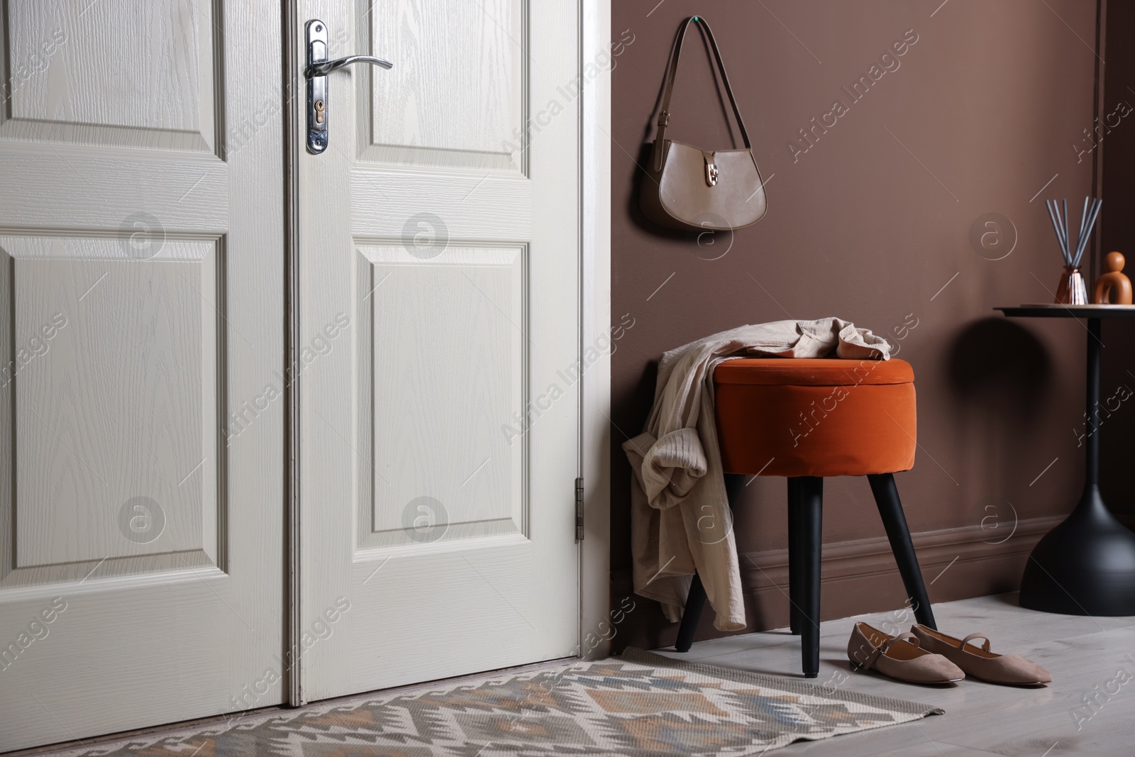 Stylish pouf with shirt and shoes near door at home Photo of Stylish pouf with shirt and shoes near door at home