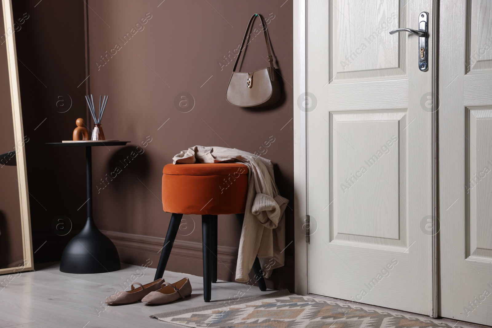 Stylish pouf with shirt and shoes near door at home Photo of Stylish pouf with shirt and shoes near door at home