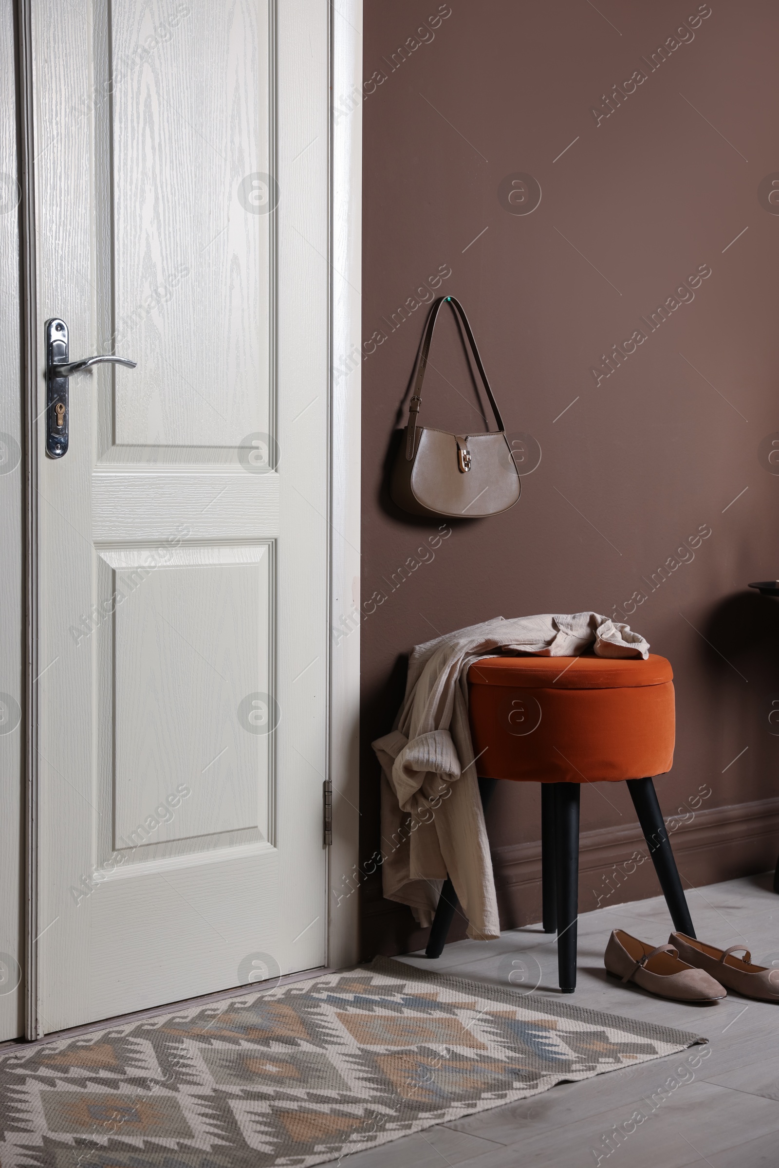 Photo of Stylish pouf with shirt and shoes near door at home