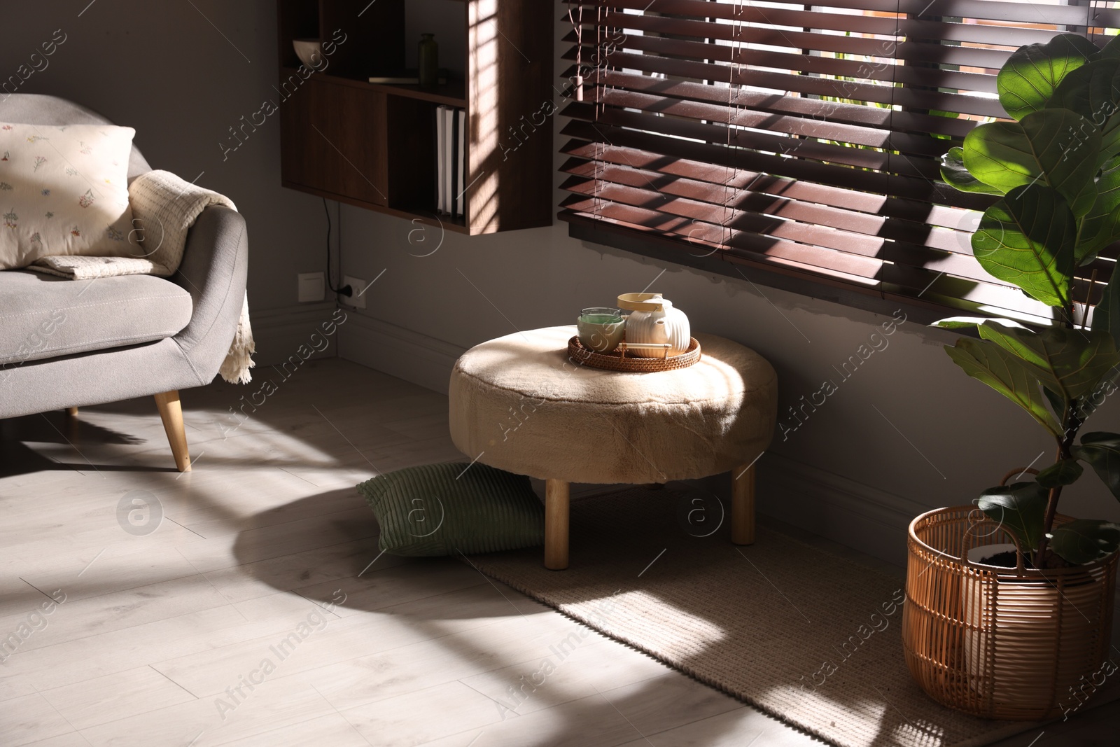 Stylish pouf with tea set in living room Photo of Stylish pouf with tea set in living room