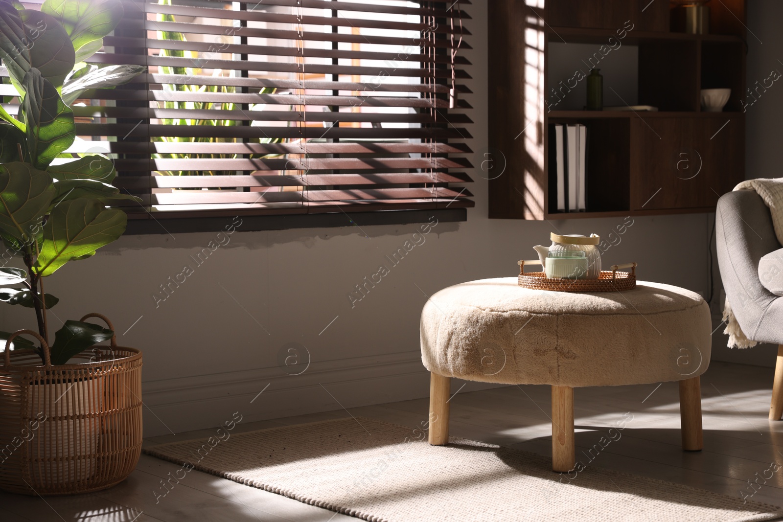 Stylish pouf with tea set in living room Photo of Stylish pouf with tea set in living room