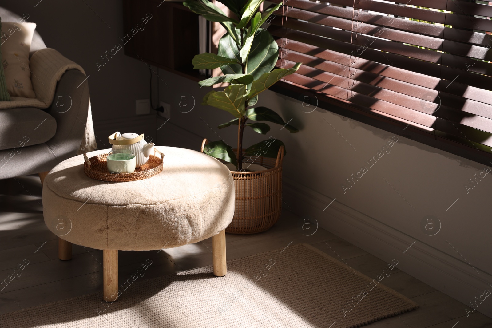 Photo of Stylish pouf with tea set in living room