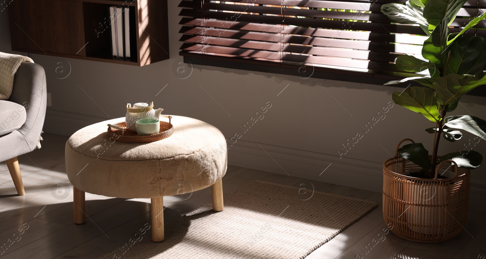 Stylish pouf with tea set in living room Photo of Stylish pouf with tea set in living room