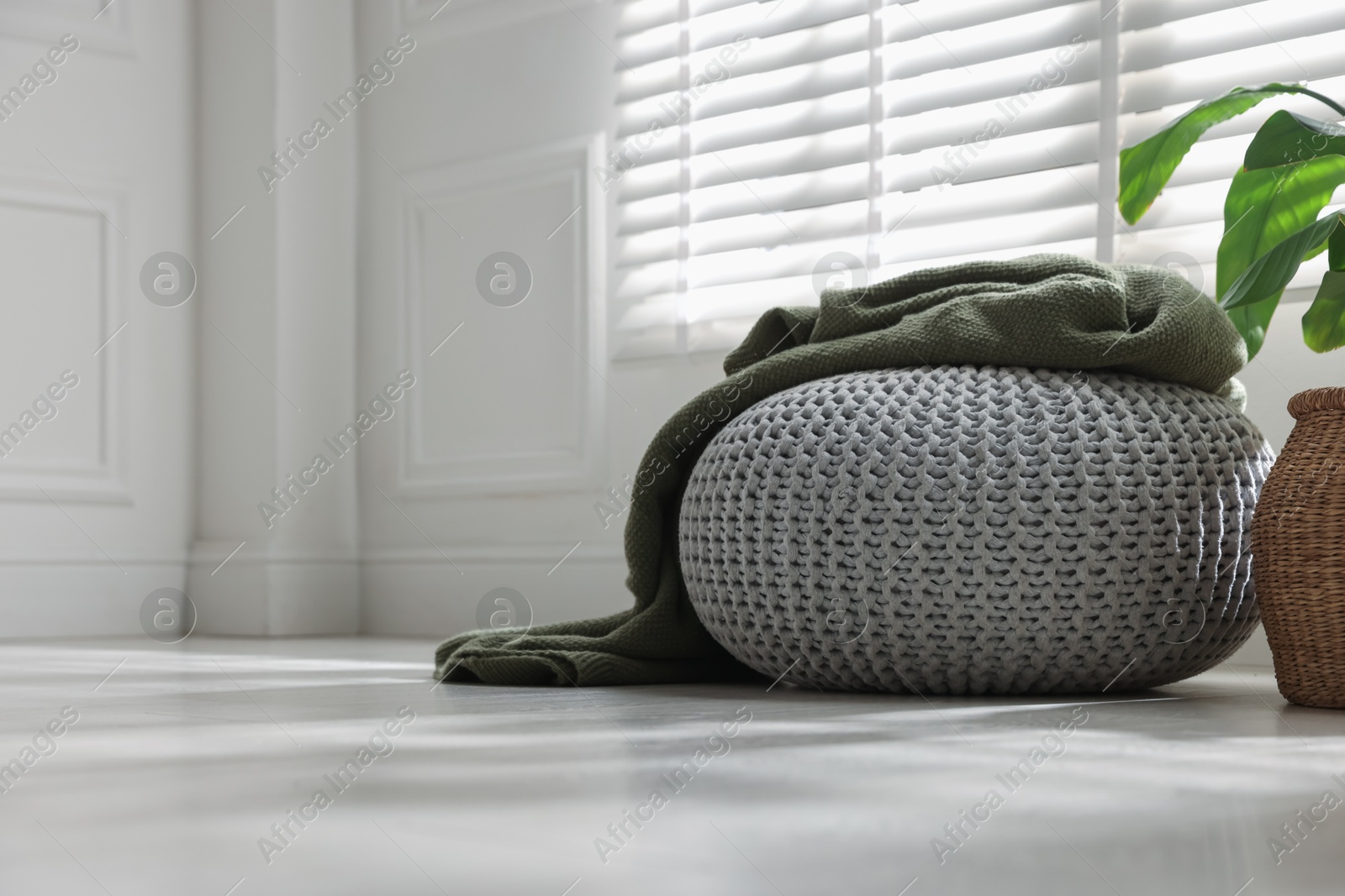 Stylish knitted pouf with plaid at home. Space for text Photo of Stylish knitted pouf with plaid at home. Space for text