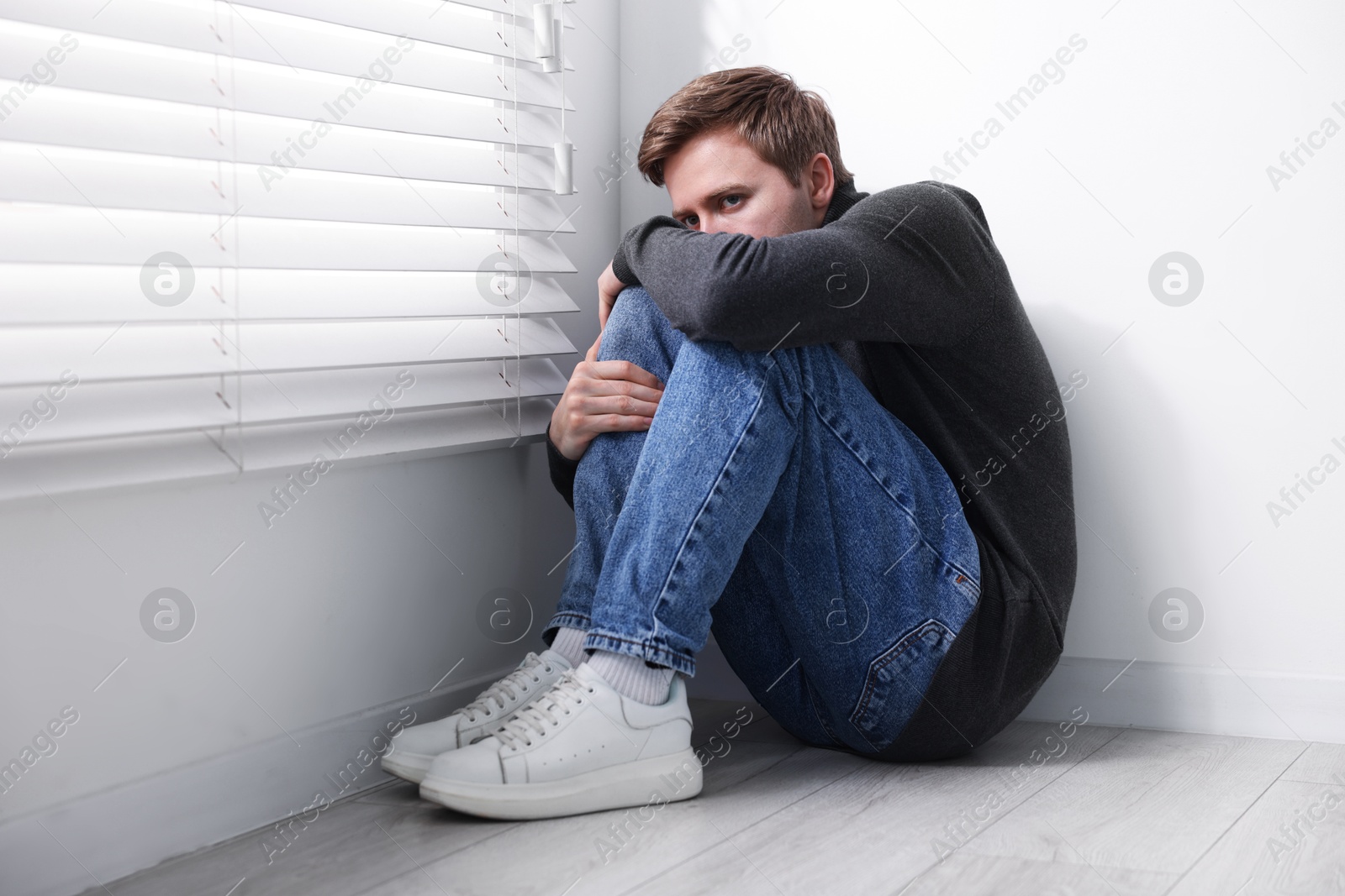 Man suffering from paranoia near window at home Photo of Man suffering from paranoia near window at home