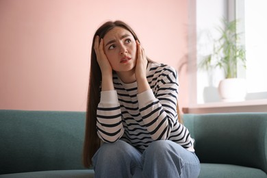 Photo of Woman suffering from paranoia on sofa at home