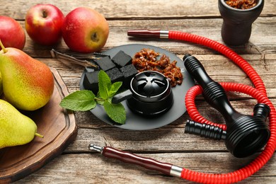 Photo of Hookah, coal and fresh fruits on wooden table, closeup