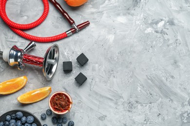 Photo of Hookah, coal and fresh fruits on grey table, flat lay. Space for text