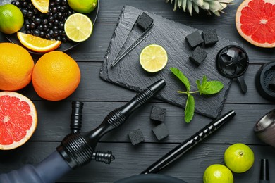 Photo of Hookah, coal and fresh fruits on black wooden table, flat lay