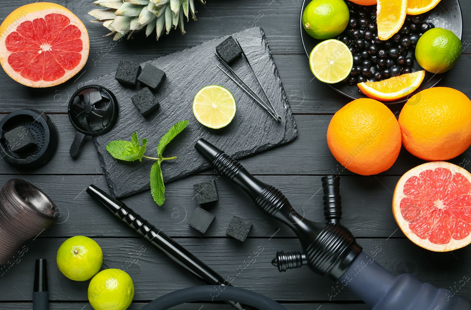 Photo of Hookah, coal and fresh fruits on black wooden table, flat lay
