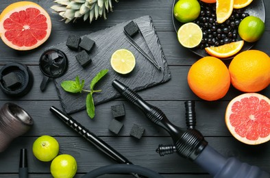 Photo of Hookah, coal and fresh fruits on black wooden table, flat lay