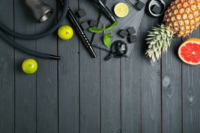 Photo of Hookah, coal and fresh fruits on black wooden table, flat lay. Space for text