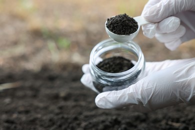 Photo of Scientist taking soil sample for research outdoors, closeup. Space for text
