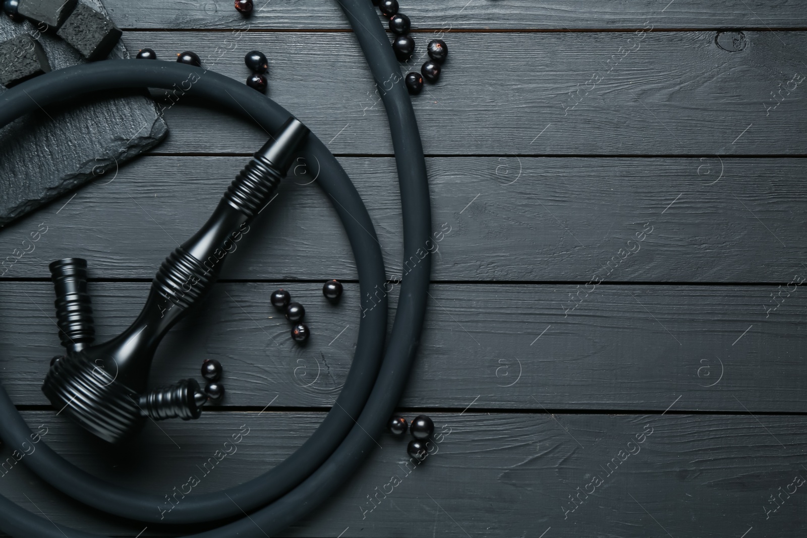 Photo of Hookah, coal and currants on black wooden table, flat lay. Space for text