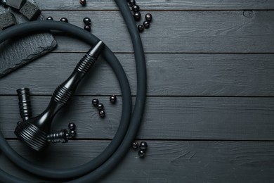 Photo of Hookah, coal and currants on black wooden table, flat lay. Space for text