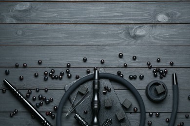 Photo of Hookah, coal and currants on black wooden table, flat lay. Space for text